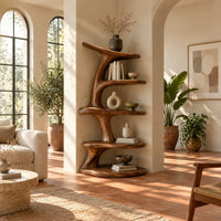 Asymmetrical bookshelf shaped like a twisting branch with stacked oval shelves in a bright living room with arched windows and plants