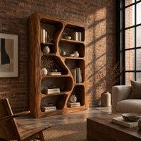 Freeform bookshelf with winding dividers and open cubbies in a thick frame in an industrial loft living room with exposed brick