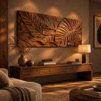 Carved wood wall art panel with overlapping tropical leaves in deep relief above a low console in an evening living room