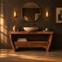 Wooden bathroom vanity on bowed legs with an open lower shelf in a dark bathroom at golden hour