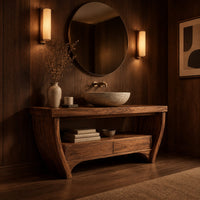 Wooden bathroom vanity on bowed legs with an open lower shelf in an evening bathroom with walnut wall paneling