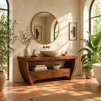 Wooden bathroom vanity on bowed legs with an open lower shelf in a bright bathroom with arched windows and plants