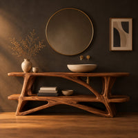 Bathroom vanity on a branching wood base with a plank top and low shelf in a dark studio against a charcoal plaster wall