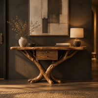 Console table with a natural edge top, small drawer unit and crossed branch legs in a dark entryway at golden hour