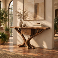 Console table with a natural edge top, small drawer unit and crossed branch legs in a bright entryway with arched windows and plants