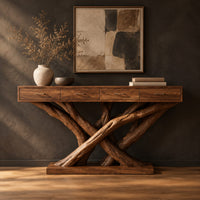Console table with four slim drawers on a base of crossed tree branches in a dark studio against a charcoal plaster wall