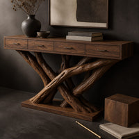 Corner detail of console table with four slim drawers on a base of crossed tree branches beside wood, brass and linen samples
