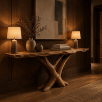 Live edge console table with a base of crossed branch shaped legs in an evening entryway with walnut wall paneling