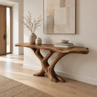 Live edge console table with a base of crossed branch shaped legs in a Scandinavian entryway with white walls