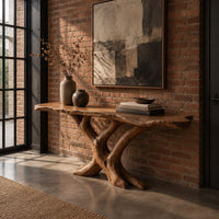 Live edge console table with a base of crossed branch shaped legs in an industrial loft entryway with exposed brick