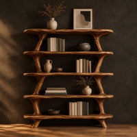 Bookshelf with five wide open shelves held by slim branch shaped uprights in a dark studio against a charcoal plaster wall