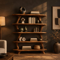 Bookshelf with five wide open shelves held by slim branch shaped uprights in a dark living room at golden hour