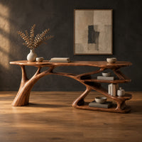 Writing desk with a branch shaped leg and stacked open shelves in a dark studio against a charcoal plaster wall