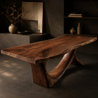 Corner detail of dining table with a flowing slab top on a branching sculpted base beside wood, brass and linen samples