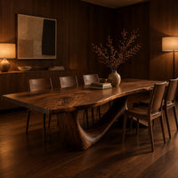 Dining table with a flowing slab top on a branching sculpted base in an evening dining room with walnut wall paneling