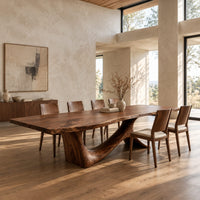 Dining table with a flowing slab top on a branching sculpted base in a bright open plan dining room
