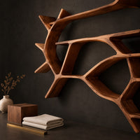 Corner detail of wall shelves shaped like a forking tree branch with many open levels beside wood, brass and linen samples
