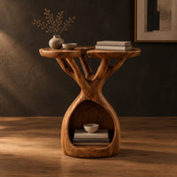 Side table with twin lobed tops on branching limbs above an open base in a dark studio against a charcoal plaster wall