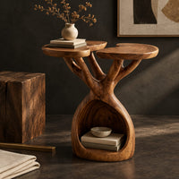 Corner detail of side table with twin lobed tops on branching limbs above an open base beside wood, brass and linen samples