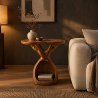 Side table with twin lobed tops on branching limbs above an open base in a dark living room at golden hour