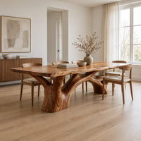 Rectangular dining table with a slab top and branching trunk base in a Scandinavian dining room with white walls