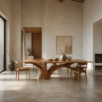 Rectangular dining table with a slab top and branching trunk base in a bright open plan dining room