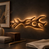 Corner detail of branching wall sconce with open cutouts and a warm glow behind the wood beside wood, brass and linen samples