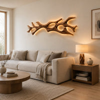 Branching wall sconce with open cutouts and a warm glow behind the wood in a Scandinavian living room with white walls