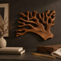 Corner detail of branching wall sconce shaped like coral with a warm glow behind its edges beside wood, brass and linen samples