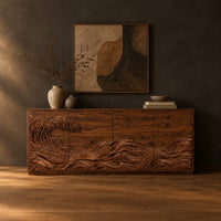 Sideboard with a carved breaking wave across the doors in a dark studio against a charcoal plaster wall