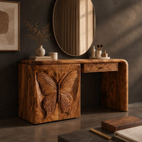 Corner detail of desk style vanity with a butterfly carved cabinet and a single drawer beside wood, brass and linen samples
