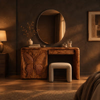 Desk style vanity with a butterfly carved cabinet and a single drawer in a dark bedroom at golden hour