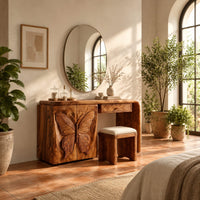 Desk style vanity with a butterfly carved cabinet and a single drawer in a bright bedroom with arched windows and plants