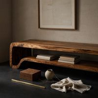 Corner detail of C curve TV cabinet with figured grain beside wood, brass and linen samples