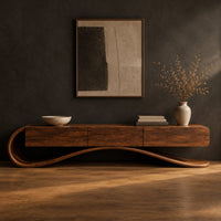 Cantilever tv stand with a long wooden body on a scrolled ribbon base in a dark studio against a charcoal plaster wall