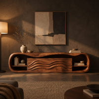 Capsule shaped tv stand with open end shelves and wave carved center panels in a dark living room at golden hour