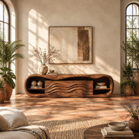 Capsule shaped tv stand with open end shelves and wave carved center panels in a bright living room with arched windows and plants
