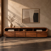 Corner detail of capsule shaped tv stand with curved ends and open top bays beside wood, brass and linen samples