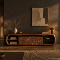 Low capsule shaped wooden tv stand with wave carved panels and open end shelves in a dark living room at golden hour