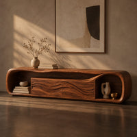 Corner detail of capsule shaped media console with wave carved center panels and open end cubbies beside wood, brass and linen samples
