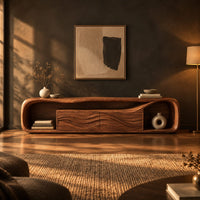 Capsule shaped media console with wave carved center panels and open end cubbies in a dark living room at golden hour
