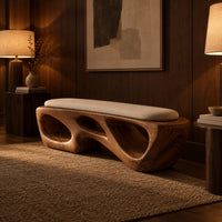 Chunky wooden bench with sculpted cutouts and a slim cream cushion on top in an evening entryway with walnut wall paneling
