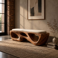 Chunky wooden bench with sculpted cutouts and a slim cream cushion on top in an industrial loft entryway with exposed brick
