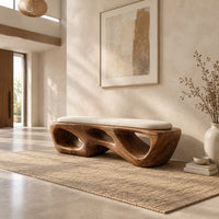 Chunky wooden bench with sculpted cutouts and a slim cream cushion on top in a bright open plan entryway