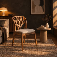 Wooden chair with a carved branch pattern back and a pale fabric seat in a dark living room at golden hour