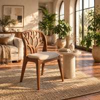 Wooden chair with a carved branch pattern back and a pale fabric seat in a bright living room with arched windows and plants