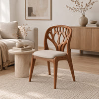 Wooden chair with a carved branch pattern back and a pale fabric seat in a Scandinavian living room with white walls