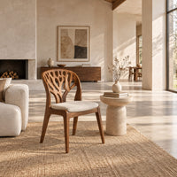 Wooden chair with a carved branch pattern back and a pale fabric seat in a bright open plan living room