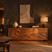 Sideboard with a breaking wave carved across three doors in a dark dining room at golden hour