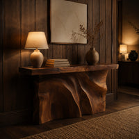 Console table with a thick slab top over a carved body of flowing ridges in an evening entryway with walnut wall paneling
